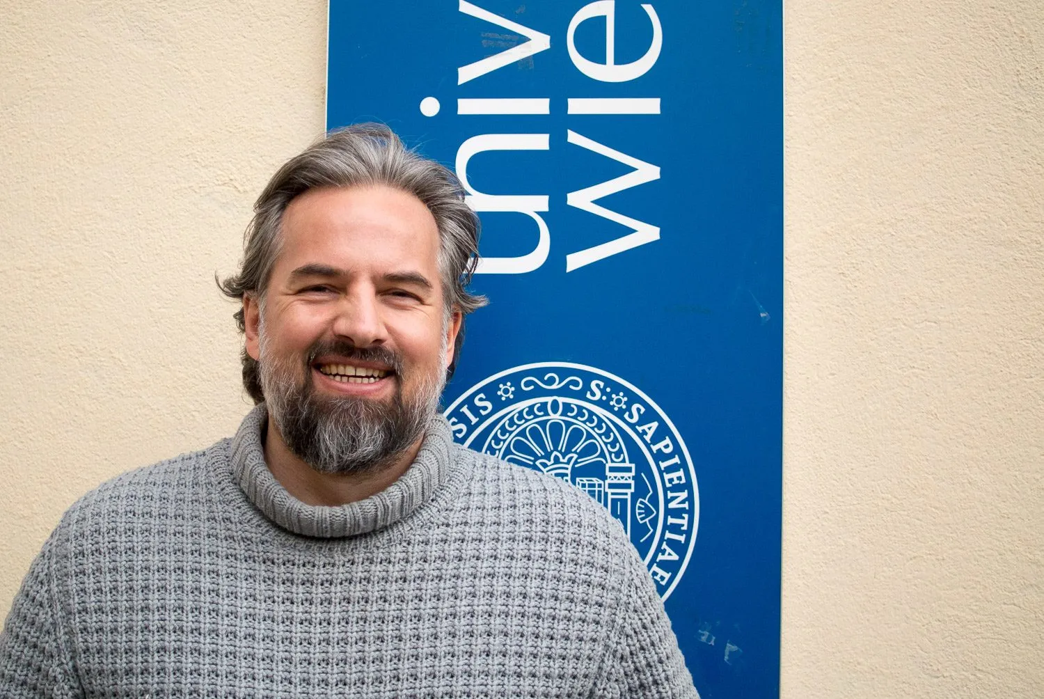 Stefan M. Schneider vor dem Banner der Universität Wien